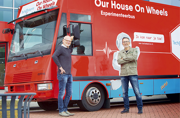 Foto (kleur) Gert-Jan en Clark voor rode bus 'Our House on Wheels'